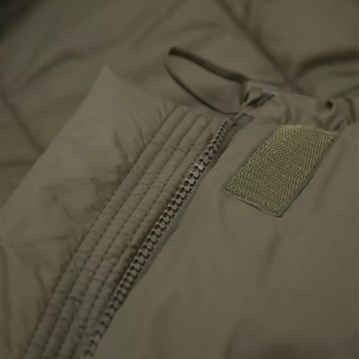 Close-up of the Carinthia Defence 4 Sleeping Bag Olive Green zipper system with reinforced stitching for durability and secure closure.