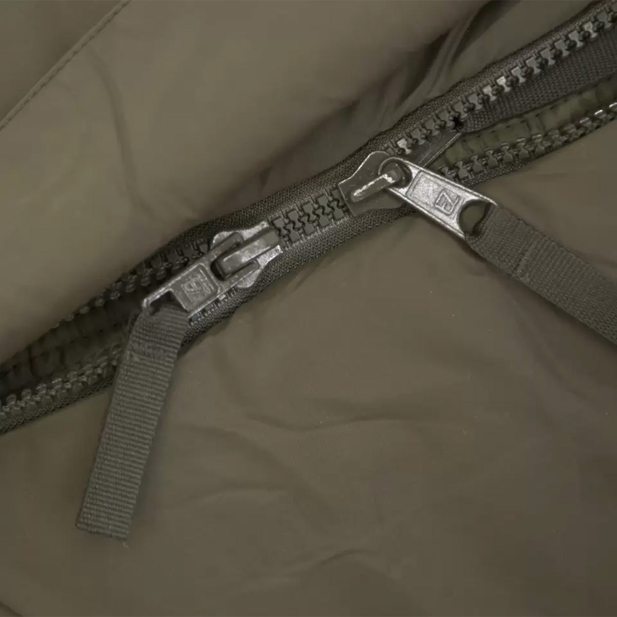 Detailed view of the Carinthia Defence 4 Sleeping Bag Olive Green dual-zipper system, ensuring easy access and ventilation control for outdoor use.