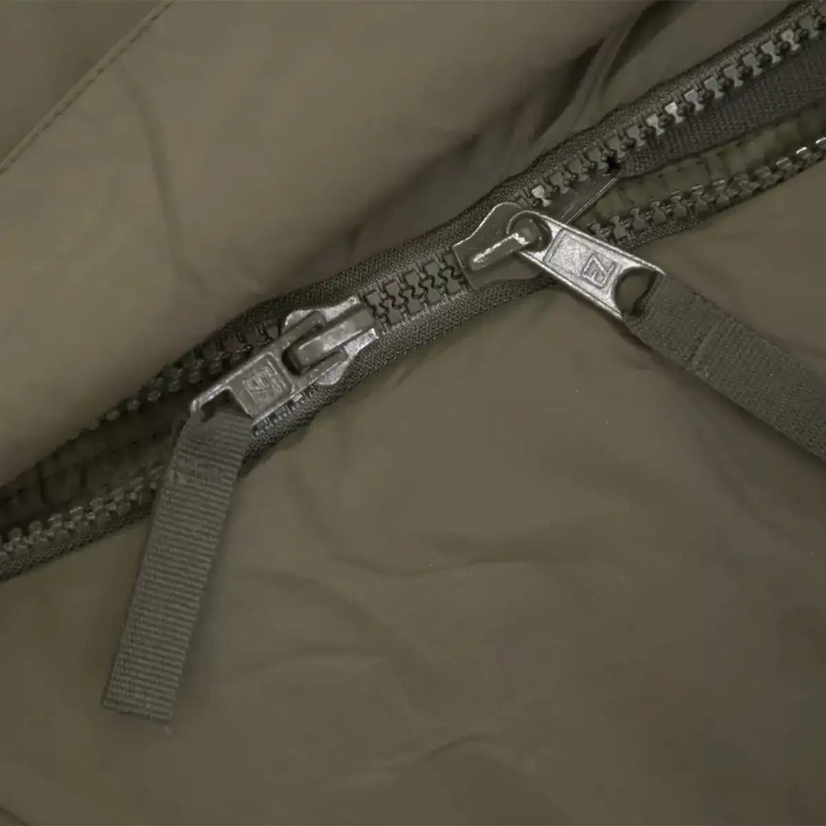 Detailed view of the Carinthia Defence 4 Sleeping Bag Olive Green dual-zipper system, ensuring easy access and ventilation control for outdoor use. from John Bull Clothing