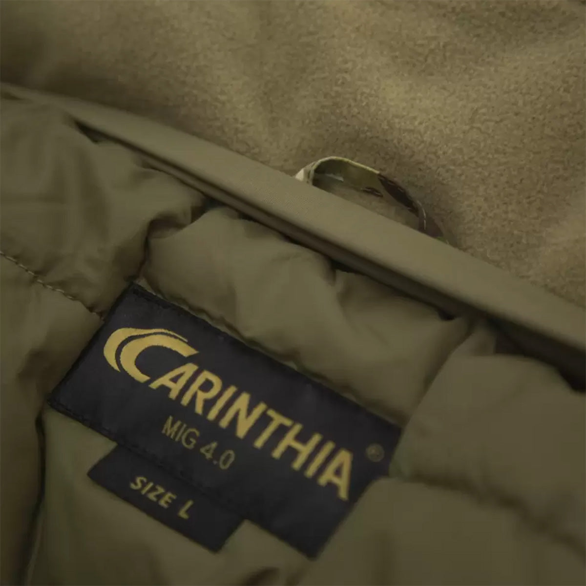 Interior label of Carinthia MIG 4.0 Jacket G-Loft Multicam, displaying brand logo and size information on insulated lining.