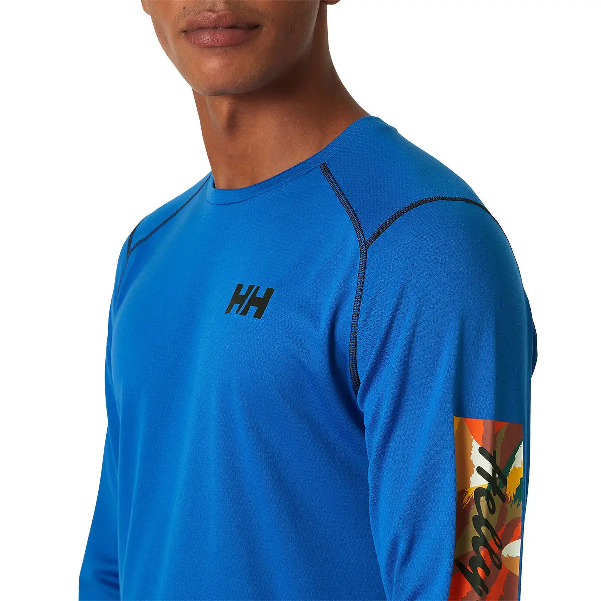Close-up of blue HH Lifa Active Crew Long Sleeve Base Layer with colorful sleeve patch and black logo, perfect for active use at John Bulls.