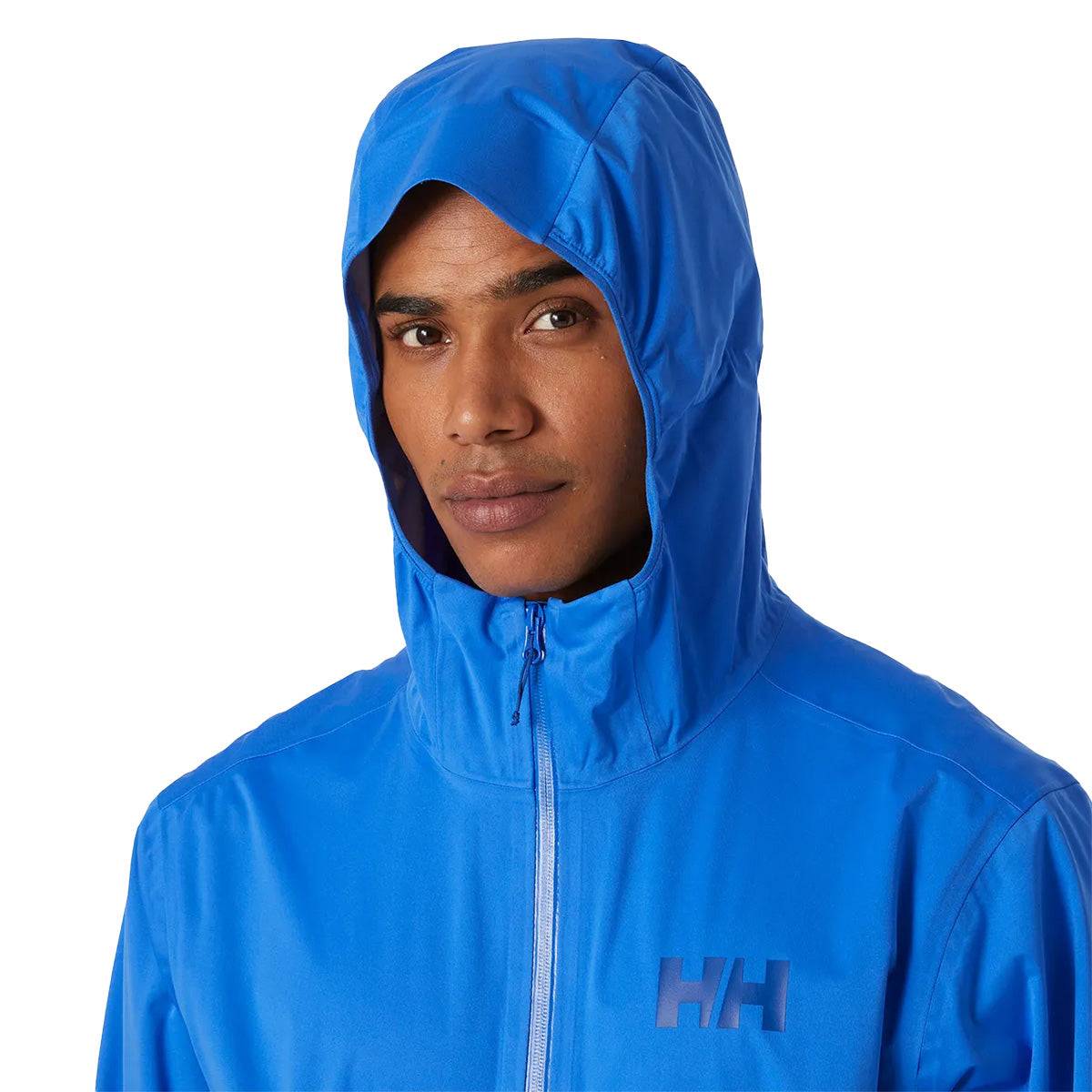 Close-up of model wearing blue Helly Hansen Mens Momentum 3 Layer Stretch Waterproof Jacket with hood up, showing waterproof hood design.