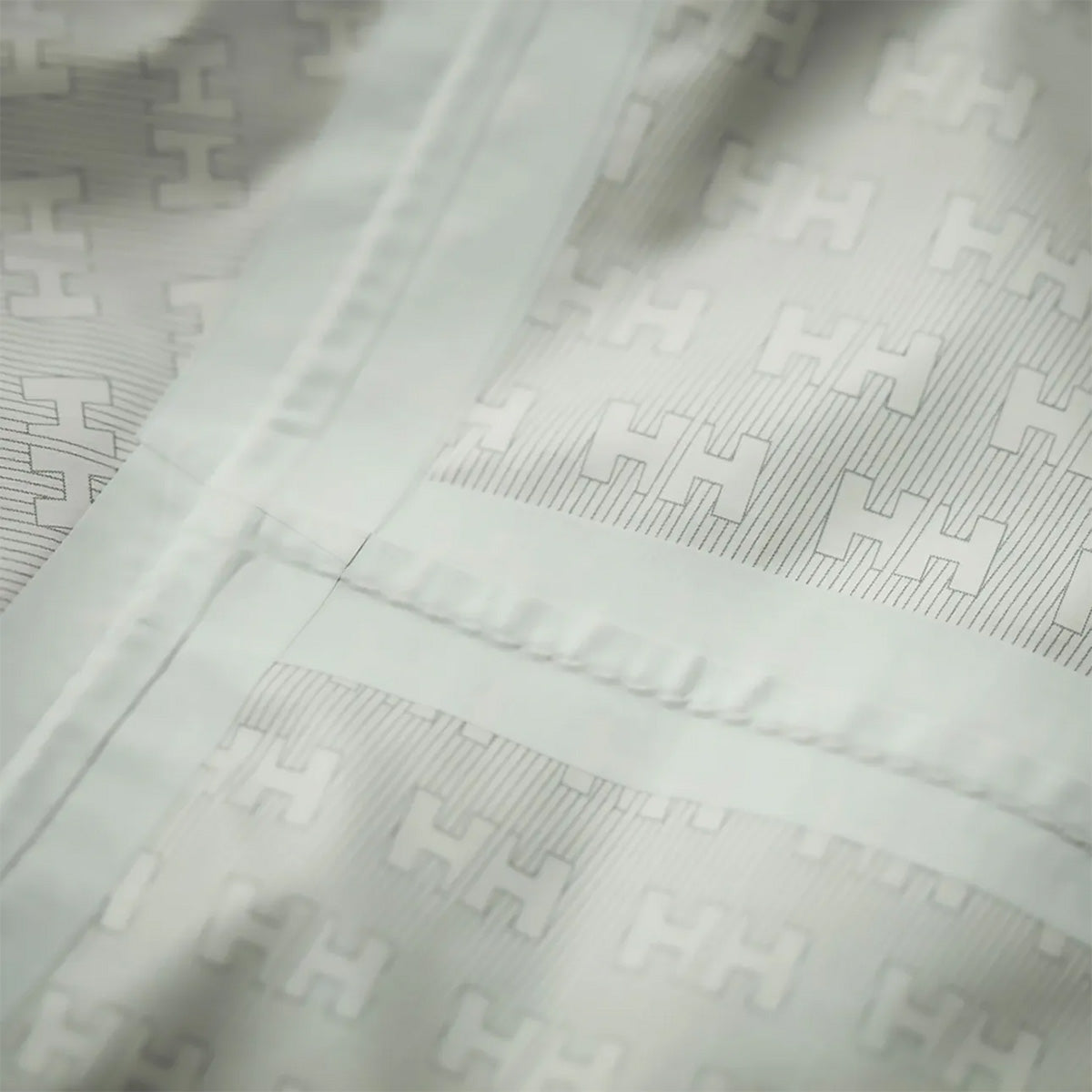 Interior seam and logo pattern of the Helly Hansen Womans Loke 2.0 Waterproof Jacket, showing quality waterproof construction.