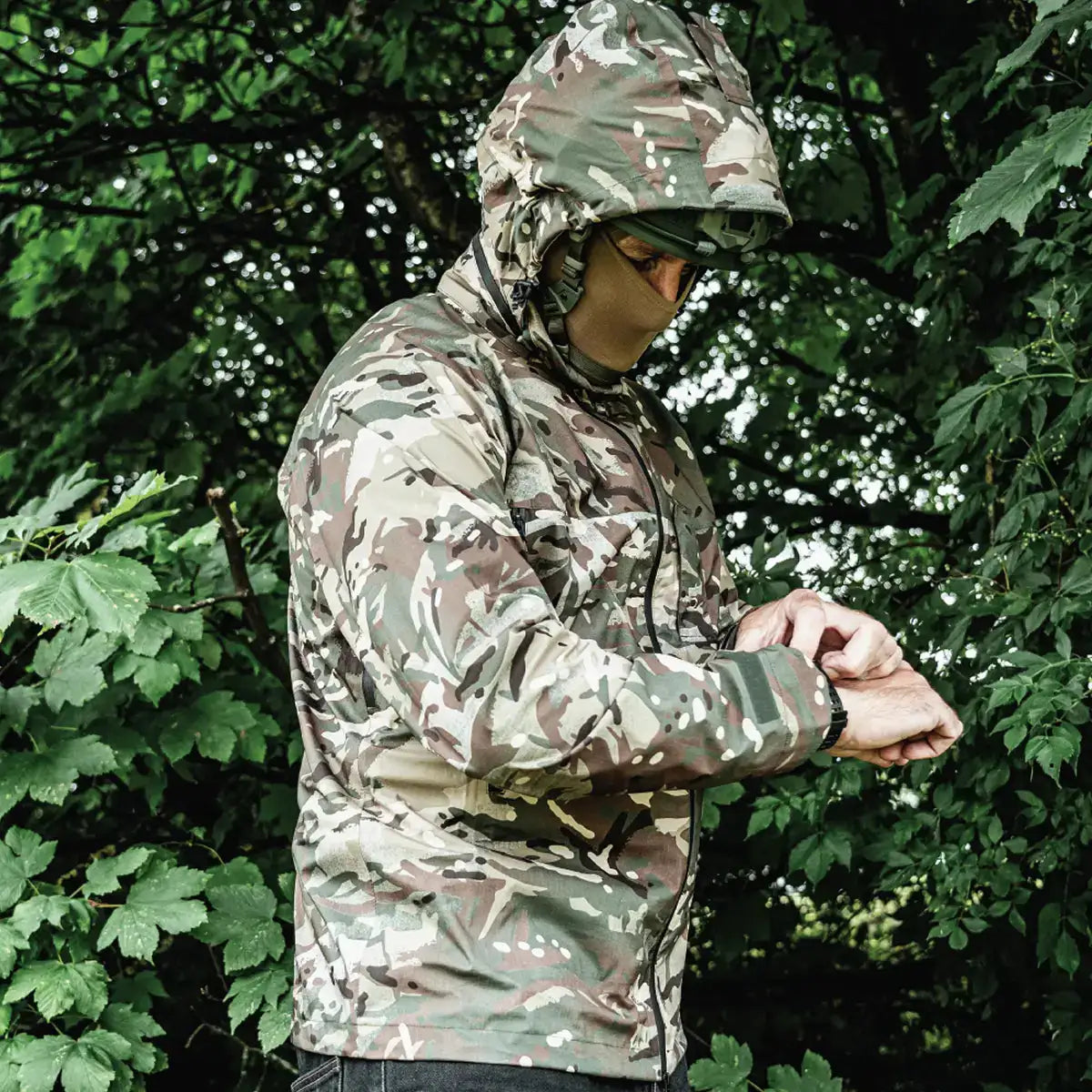 Model wearing Highlander Cyclone Pro Waterproof Jacket in camo outdoors, demonstrating its fit and weatherproof performance. from John Bull Clothing
