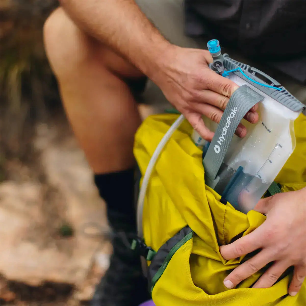 Close-up of HydraPak Contour Clear Water Reservoir being packed into a yellow hiking bag, emphasizing ease of use and outdoor readiness. from John Bull Clothing