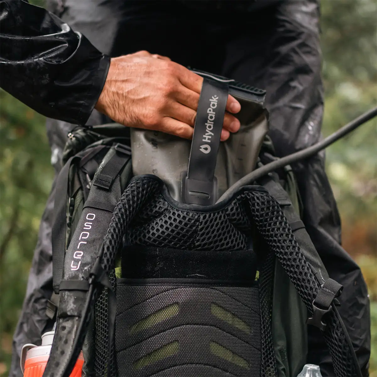 User inserting HydraPak Force Tactical Grey Water Reservoir into hiking backpack, built for extreme outdoor conditions | John Bulls