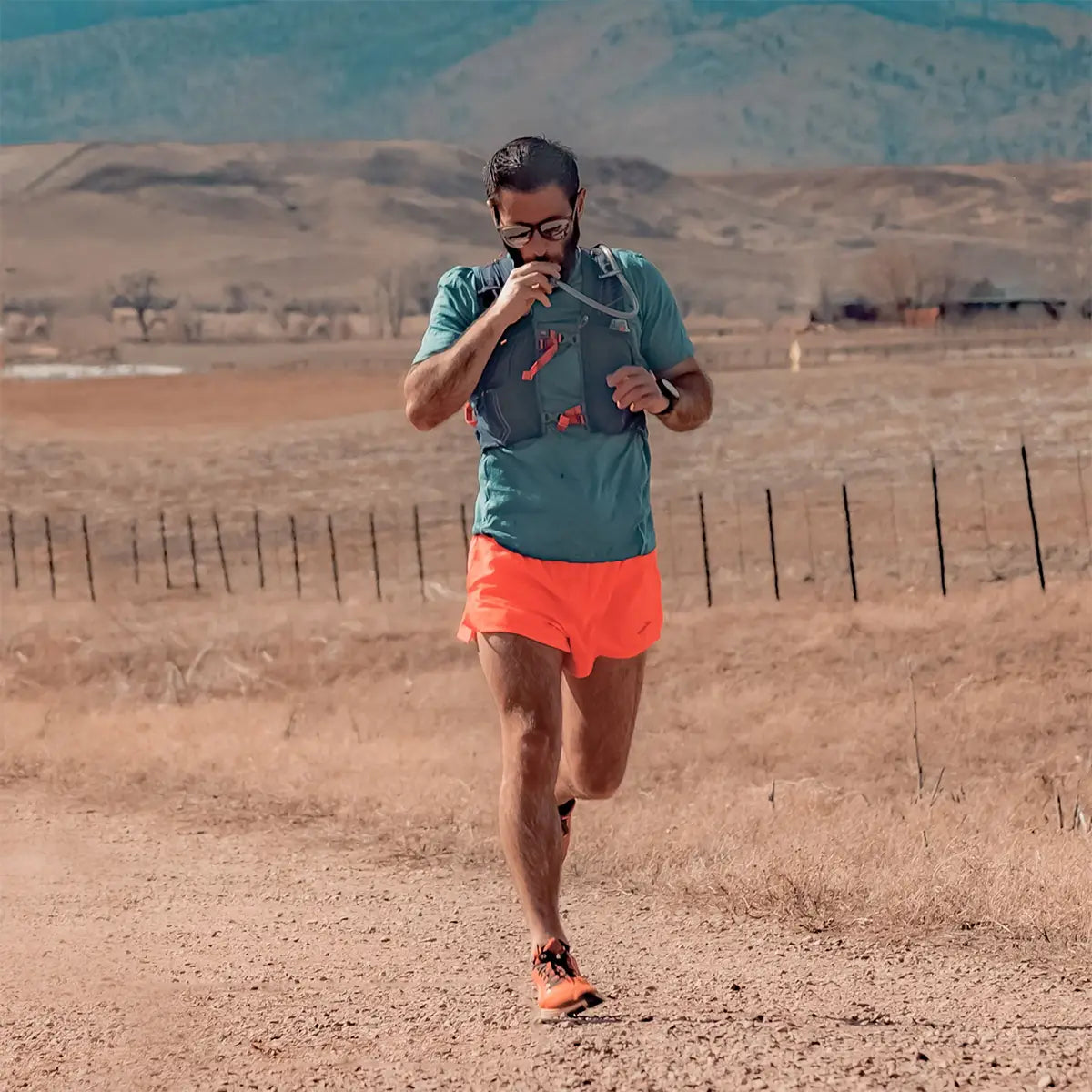 Trail runner drinking from the HydraPak Velocity Hydration Water Reservoir while running, showing its convenience for endurance sports.