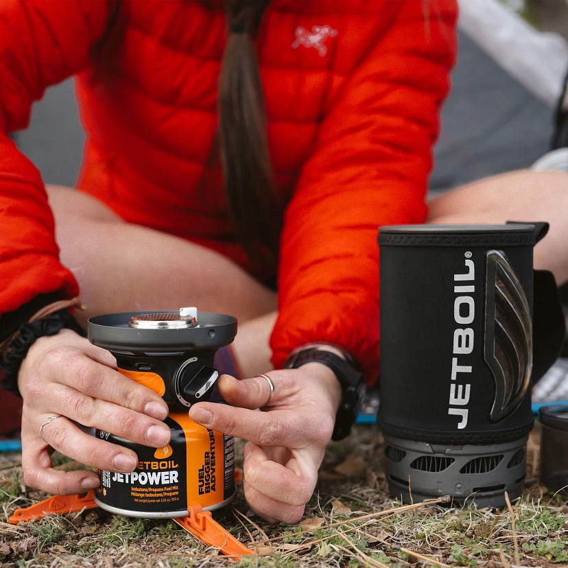 Camper assembling the Jetboil Flash 1.0L Fast Boil Stove System, demonstrating its easy setup for outdoor cooking.