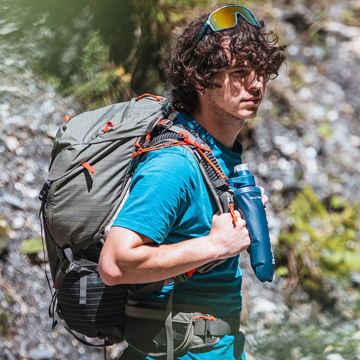 Hiker carrying Katadyn BeFree AC Water Filter Bottle 500ml Slate Blue on a trail, showcasing its portability and outdoor adventure readiness.