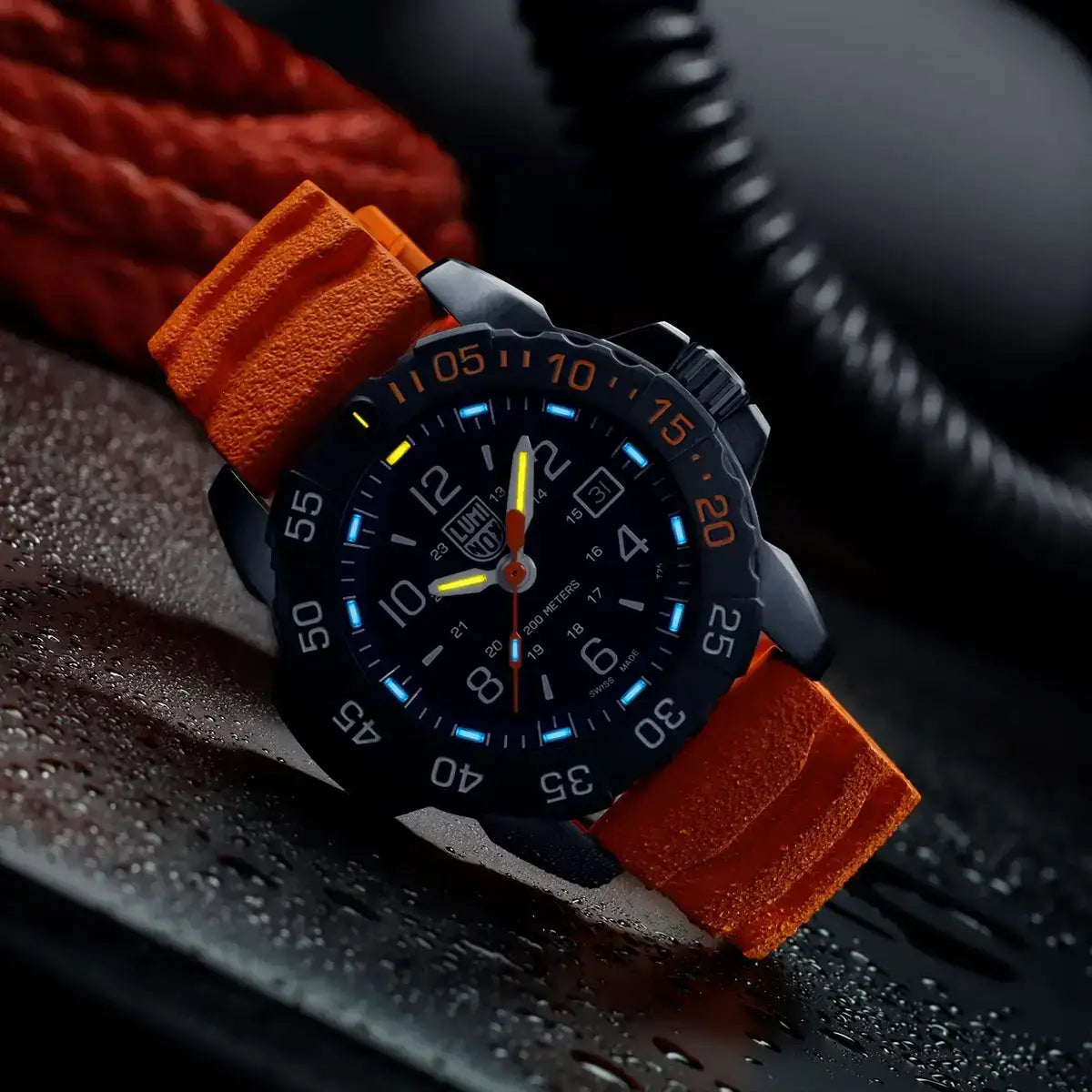 Black analogue watch with orange and yellow accents, luminous hands, and a textured orange strap, water-resistant up to 200 meters