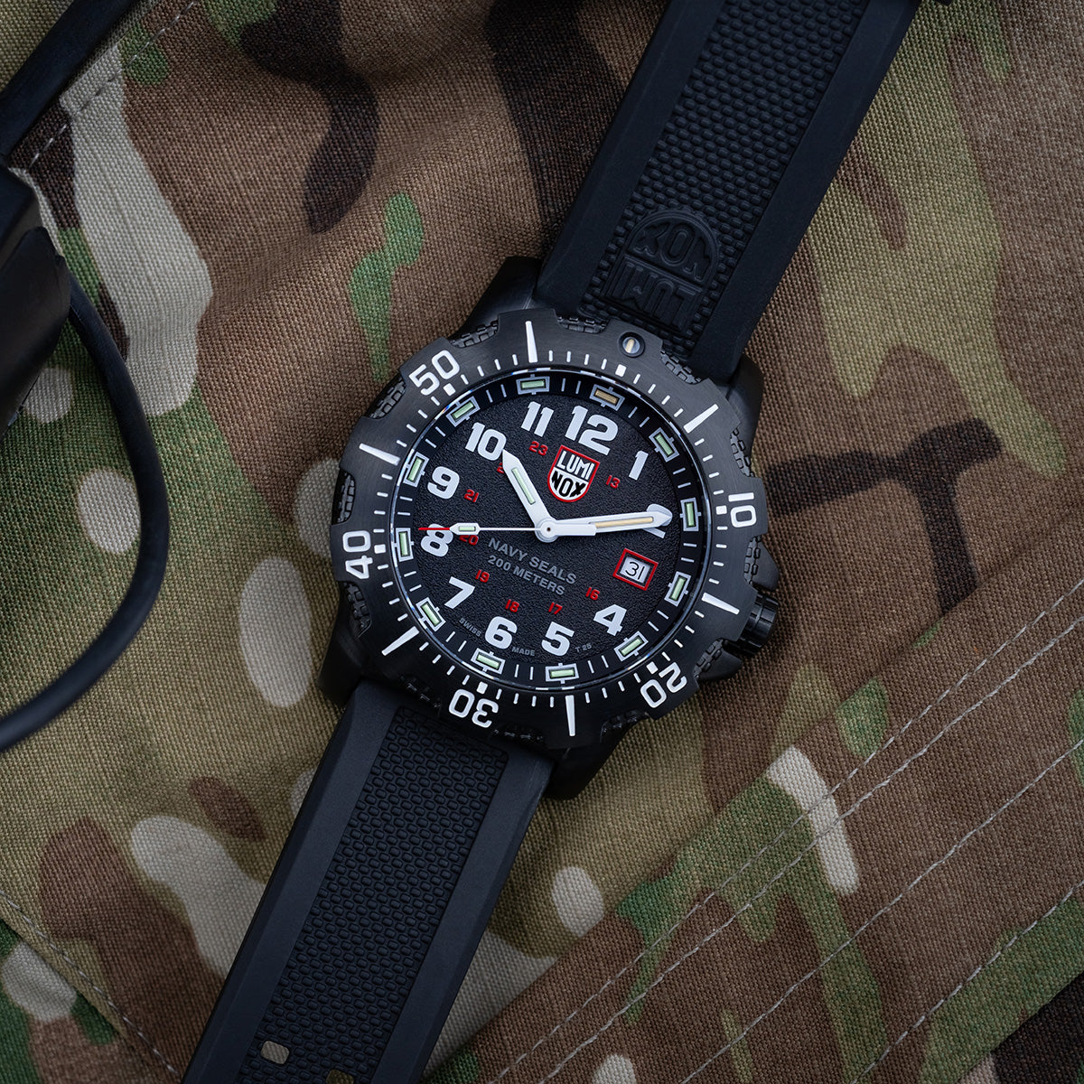 Luminox Navy Series Watch 4230 Series XS.4231.SET laid on camouflage fabric, showcasing its rugged black case, rubber strap, and military-inspired design.