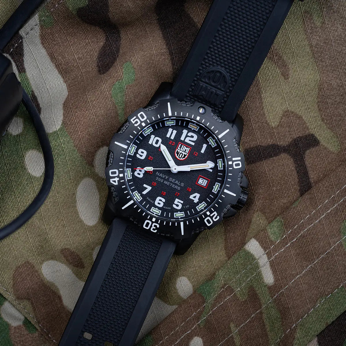 Luminox Navy Series Watch 4230 Series XS.4231.SET laid on camouflage fabric, showcasing its rugged black case, rubber strap, and military-inspired design. from John Bull Clothing