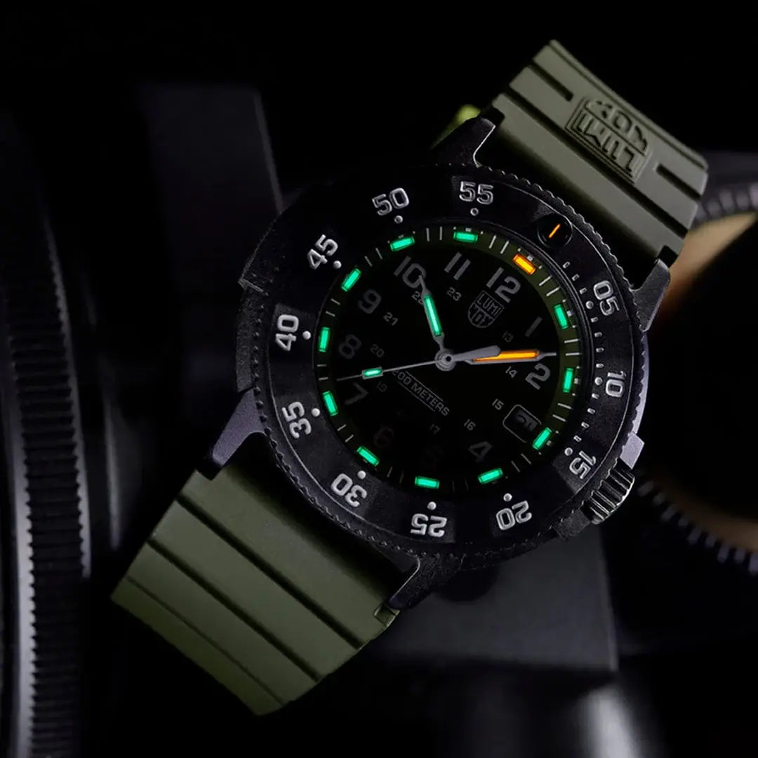 Luminox Navy Seal 3001 Dive Watch illuminated in low light, featuring green and orange tritium tubes for 24/7 readability.