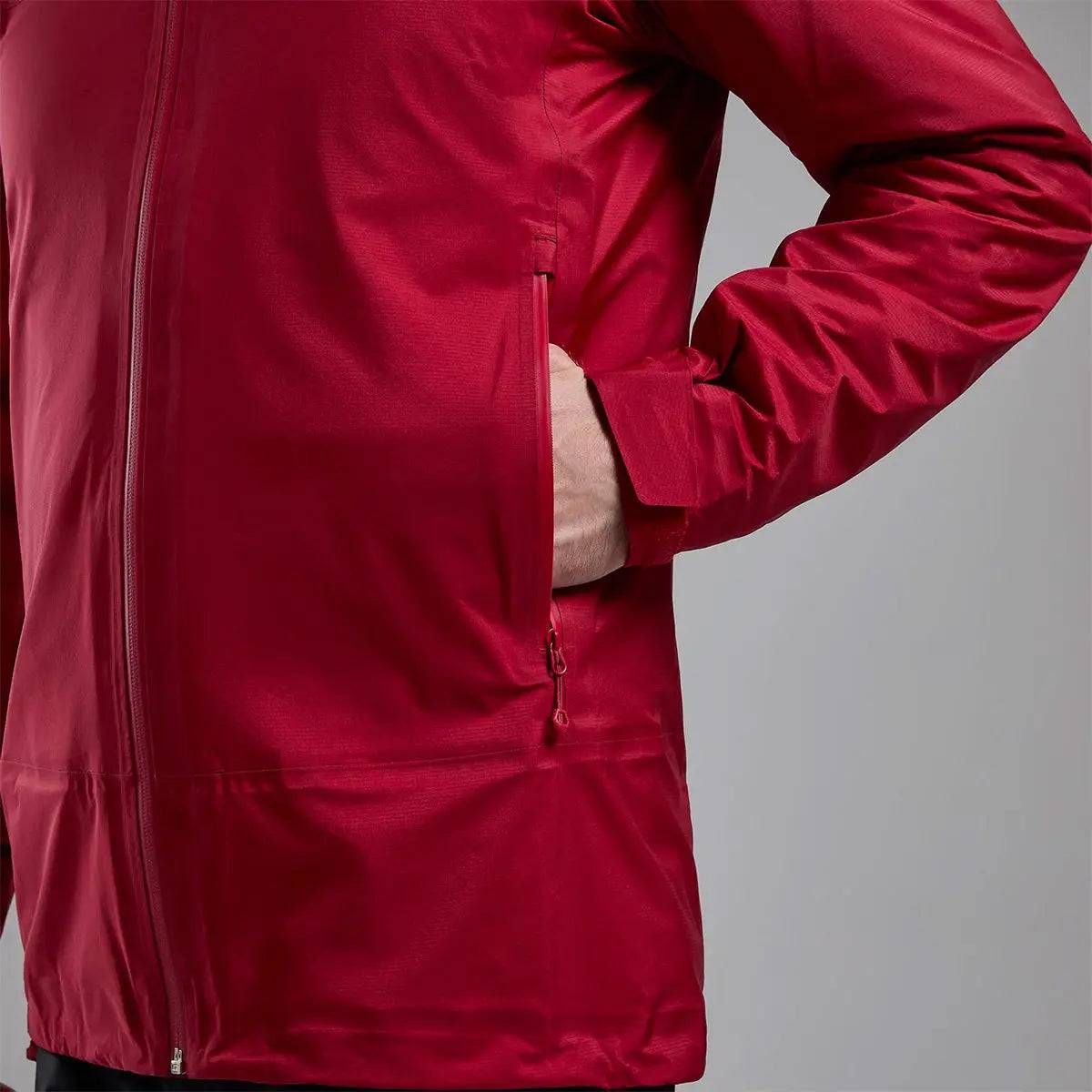 Close-up of Montane Mens Cetus Lite Waterproof Jacket in red, focusing on the zippered side pocket for secure storage during outdoor activities.