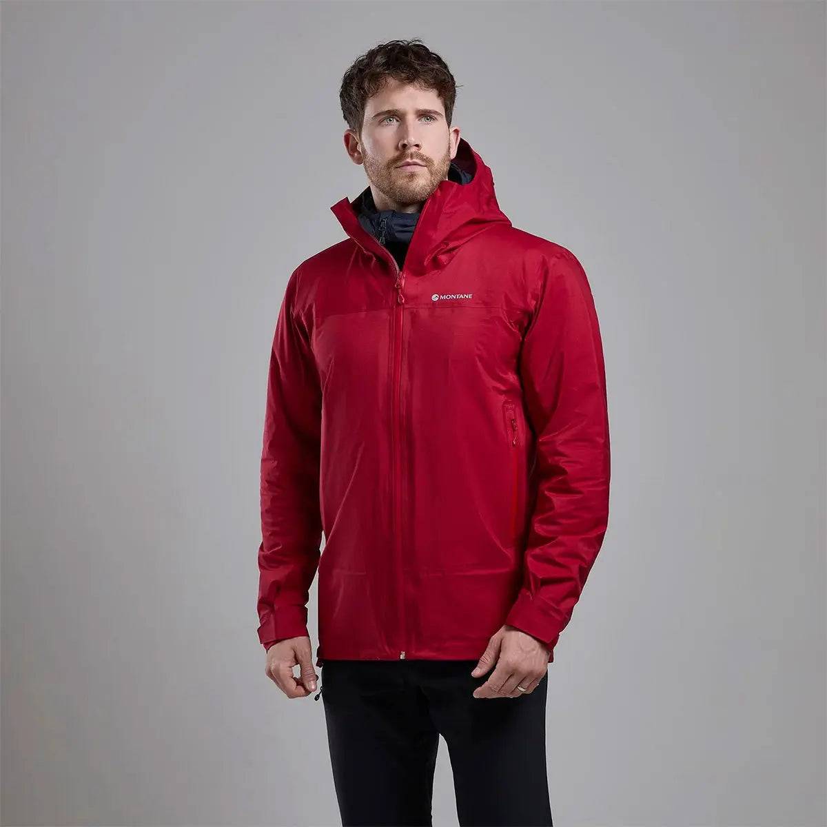 Model wearing Montane Mens Cetus Lite Waterproof Jacket in red, highlighting its ergonomic fit and protective outer shell for outdoor activities.