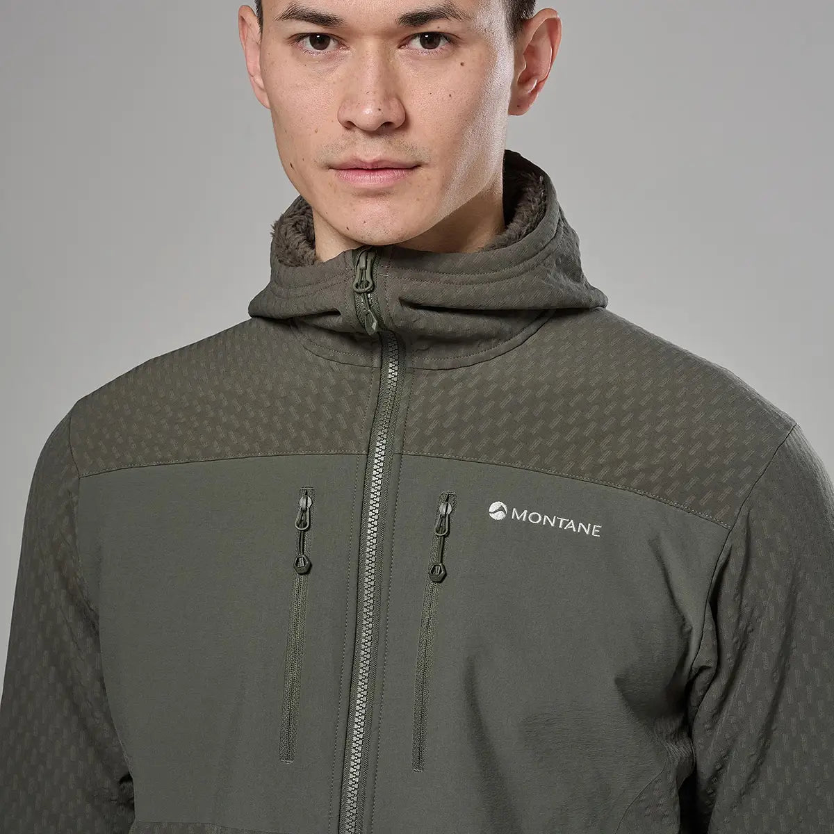 Male model wearing Montane outdoor jacket with high collar and hood, in grey and navy, designed for active outdoor use