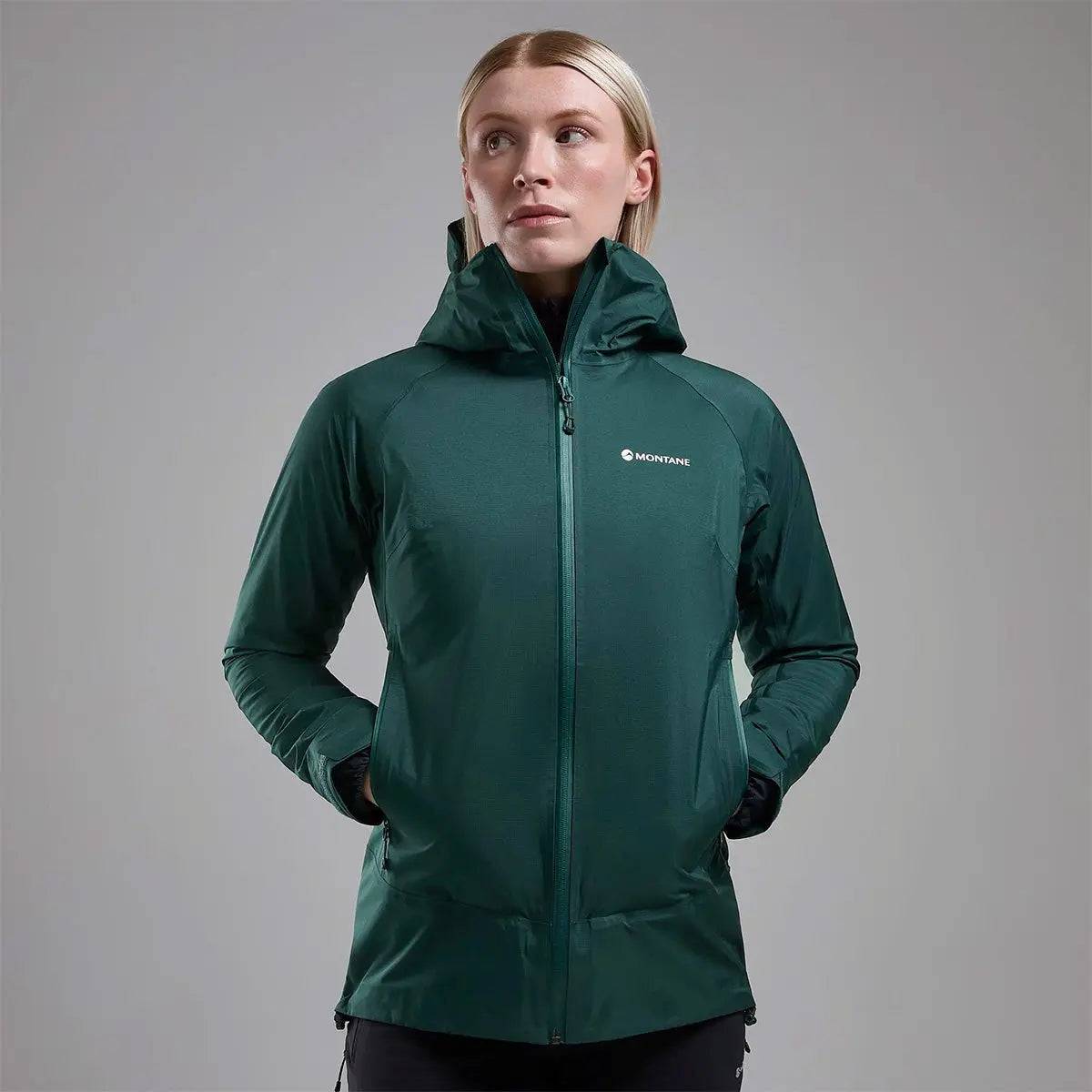 Model wearing Montane Women's Cetus Lite Waterproof Jacket in dark green, showcasing its tailored fit and functional design.