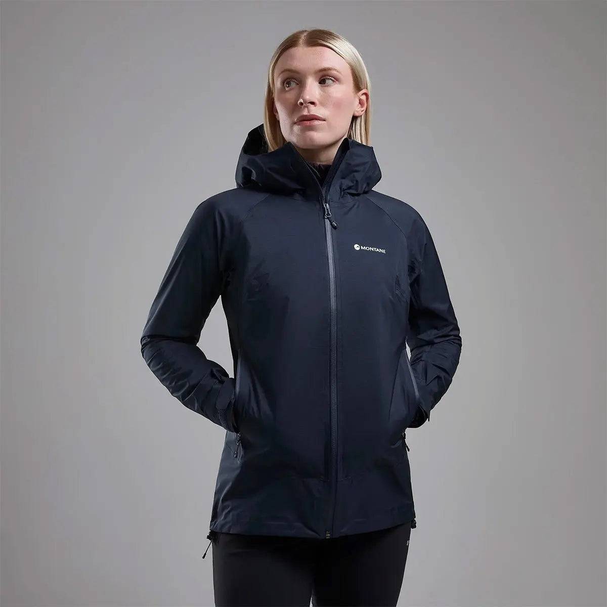Model wearing Montane Women's Cetus Lite Waterproof Jacket in black, highlighting its sleek design and practical outdoor wearability.
