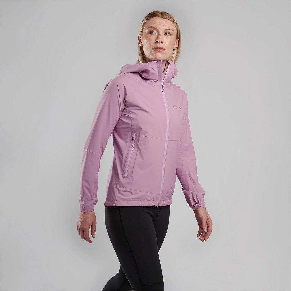 Woman walking in pink Montane Womans Minimus Lite Waterproof Jacket, lightweight and breathable outerwear for active outdoor lifestyles.