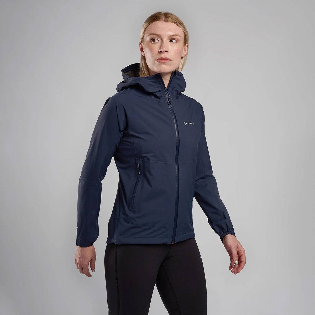Woman modeling navy Montane Womans Minimus Lite Waterproof Jacket, designed for female endurance athletes needing breathable waterproof outerwear.