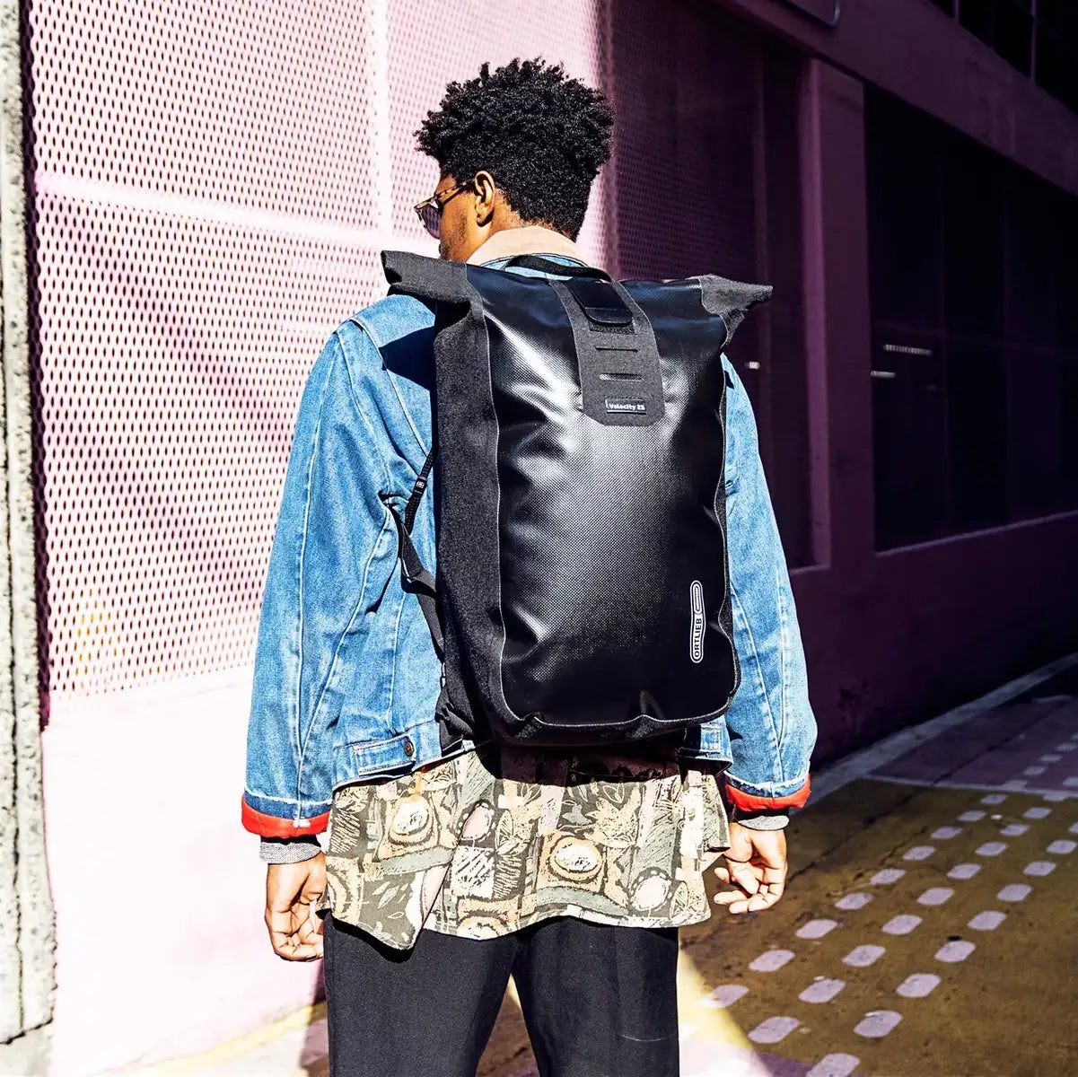 Model wearing Ortlieb Velocity 23L Dry Backpack in black, showcasing its urban style and functional design for everyday adventures.