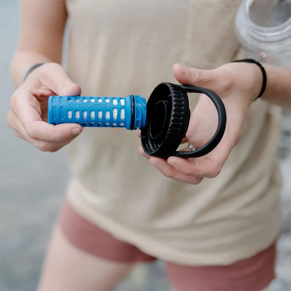 Hands holding Platypus DayCap In Water Bottle Filter, showcasing its detachable filtration system for easy cleaning and use.