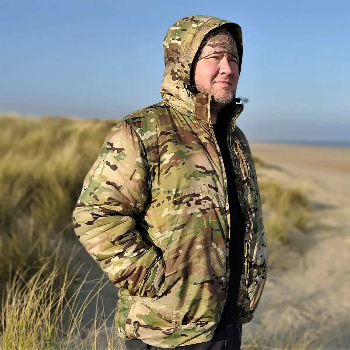 Man wearing Snugpak Spearhead Midweight Insulated Jacket WGTE Multicam outdoors, showcasing its field-ready design and weather protection.