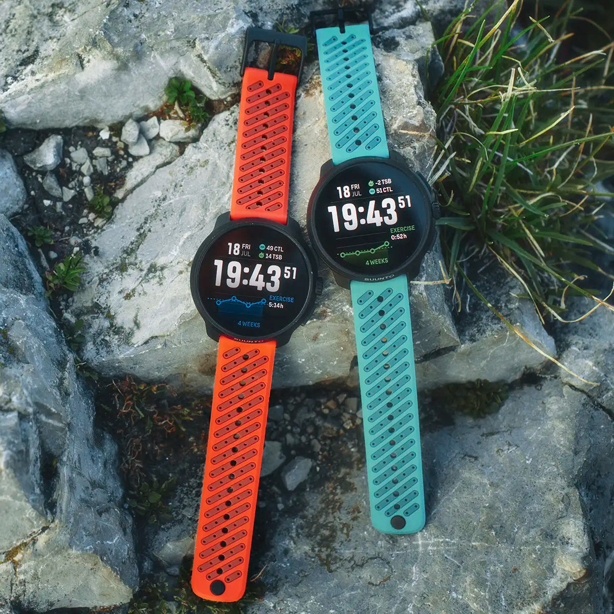 Suunto Race 2 GPS Fitness Watches in orange and teal straps placed on rocks, highlighting rugged outdoor design and durability.