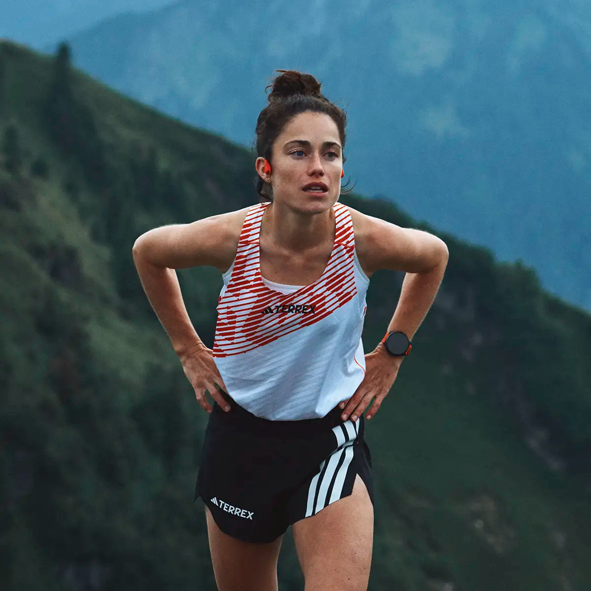 Female athlete wearing Suunto Race 2 GPS Fitness Watch during mountain run, showcasing its use in endurance sports.