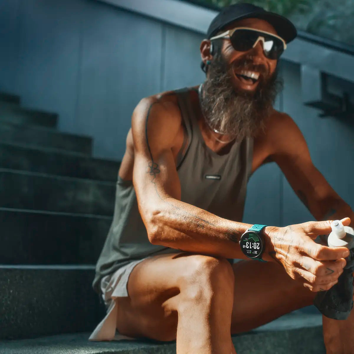Male runner resting on stairs wearing Suunto Race 2 GPS Fitness Watch, emphasizing comfort and performance tracking.
