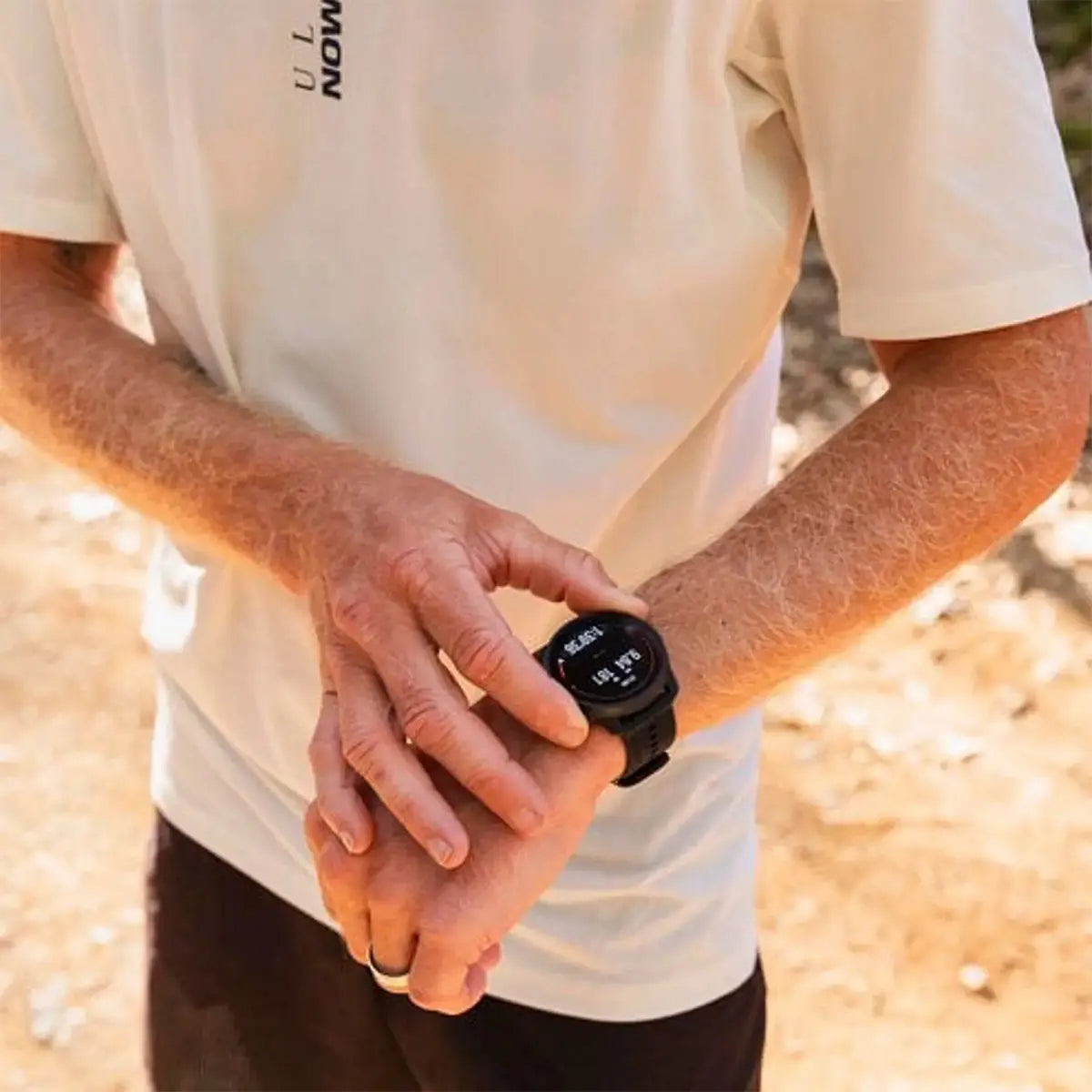Man adjusting Suunto Race S GPS Sports Watch on wrist outdoors. Designed for real-time tracking during active adventures.