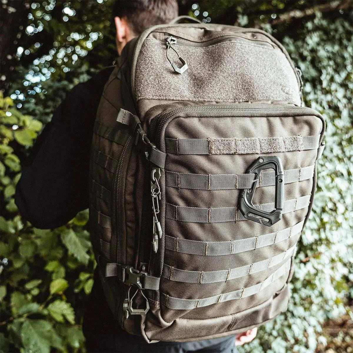 Person wearing the Highlander Harrier 45L Clamshell Backpack in olive green, showcasing its large capacity, tactical design, and outdoor durability.