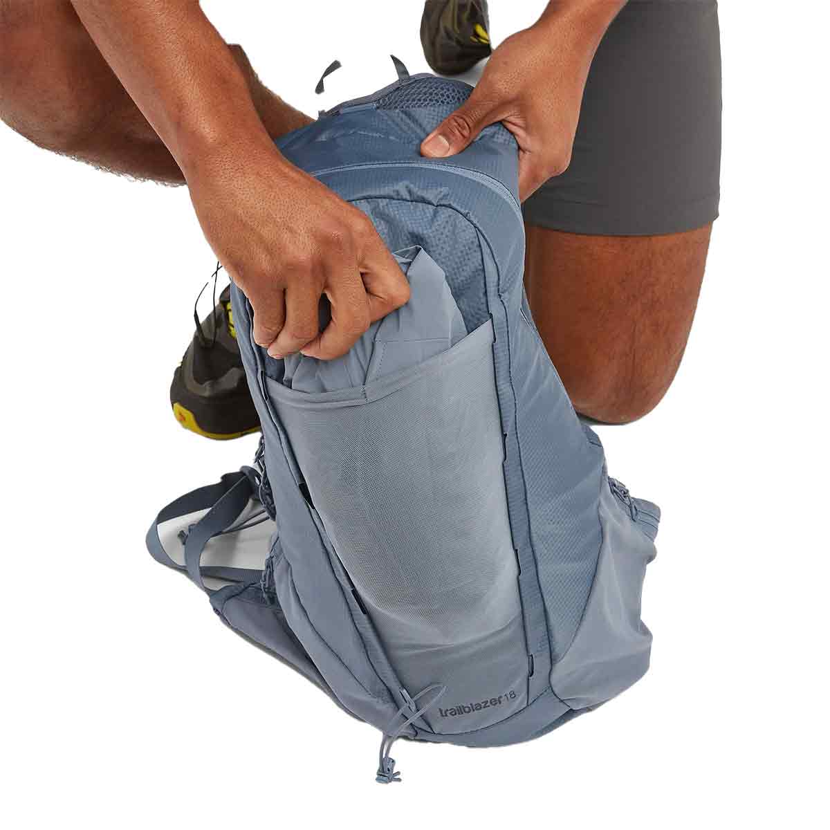 Man accessing the main compartment of the Montane Trailblazer 18L Backpack, demonstrating its spacious storage.