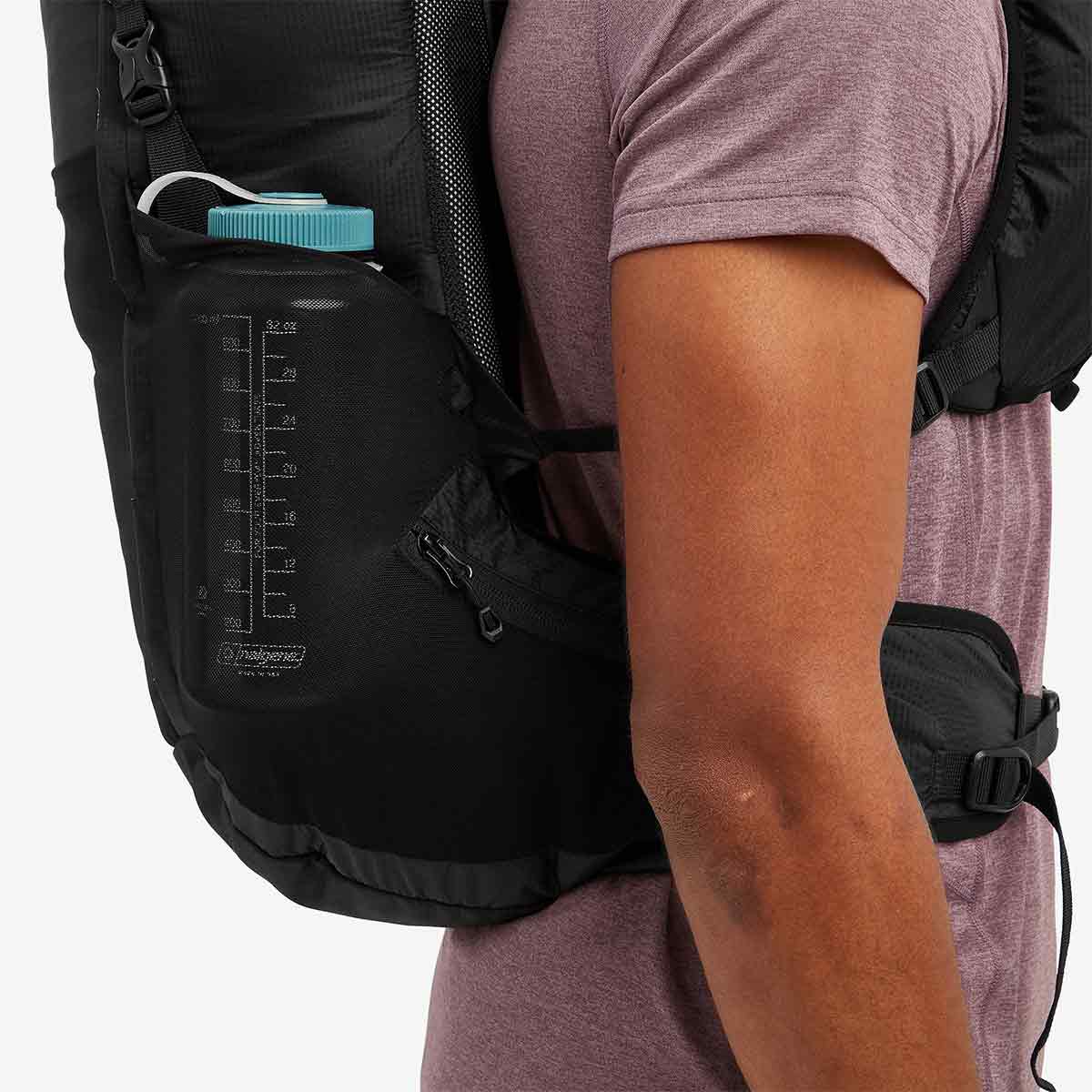 Side view of the Montane Trailblazer 25L Rucksack in black, highlighting a water bottle pocket with volume markings for hydration tracking.