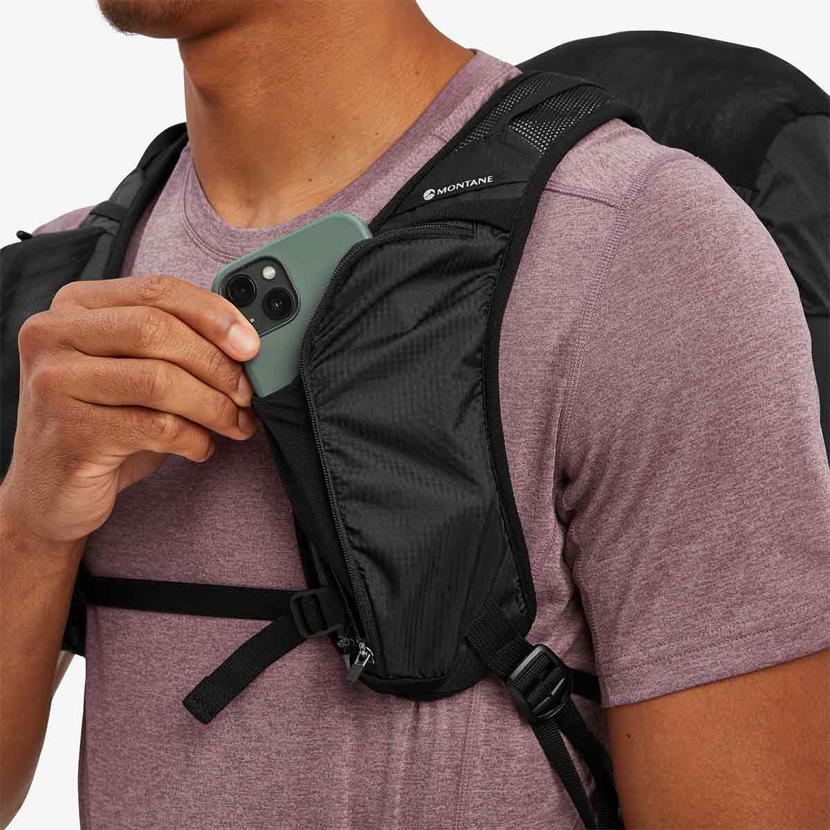 Close-up of a model storing a smartphone in the Montane Trailblazer 25L Rucksack’s front pocket, showcasing its convenient storage options.