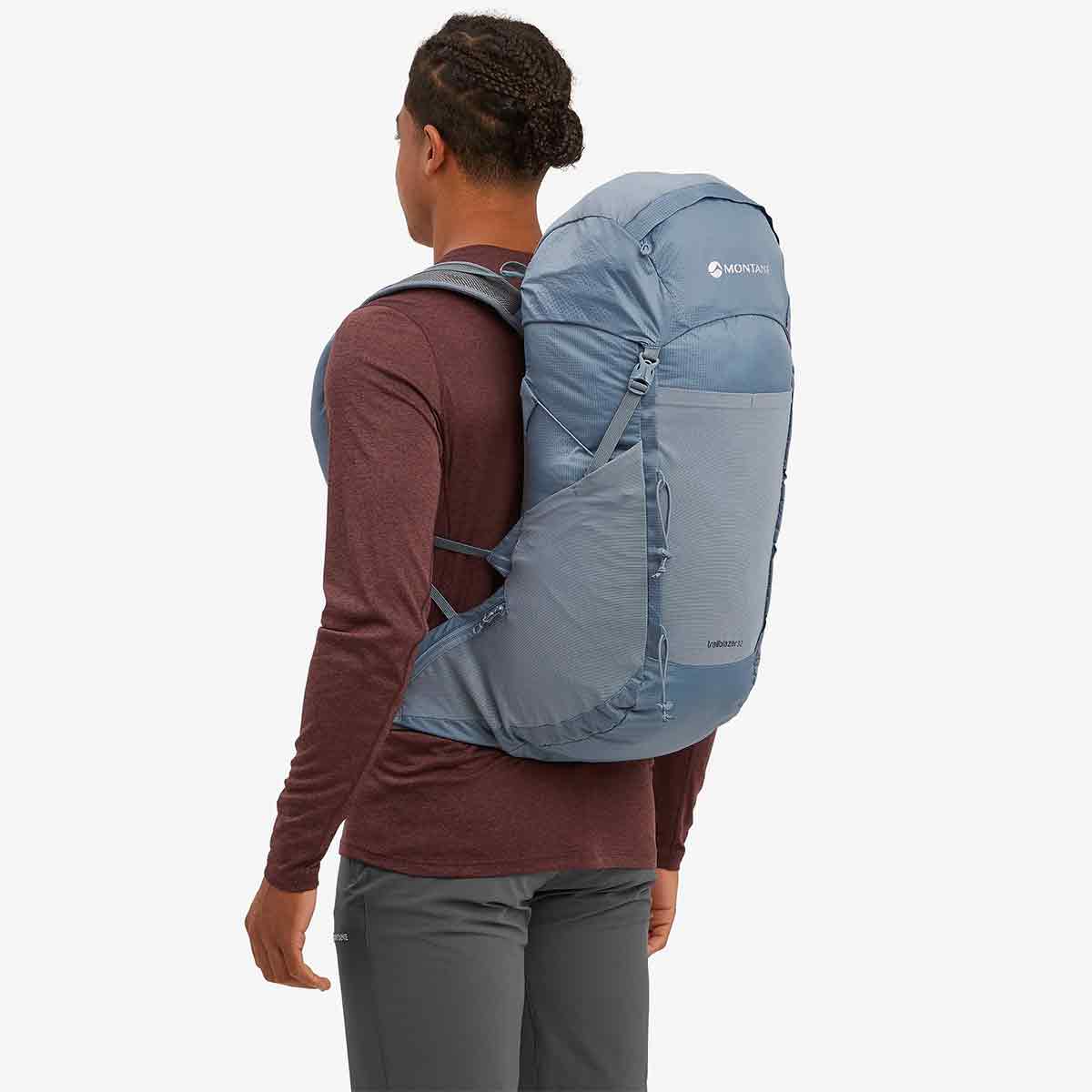 Rear view of a model wearing the Montane Trailblazer 32 Litre Backpack in blue, showing its contoured back panel and lightweight design for hiking.