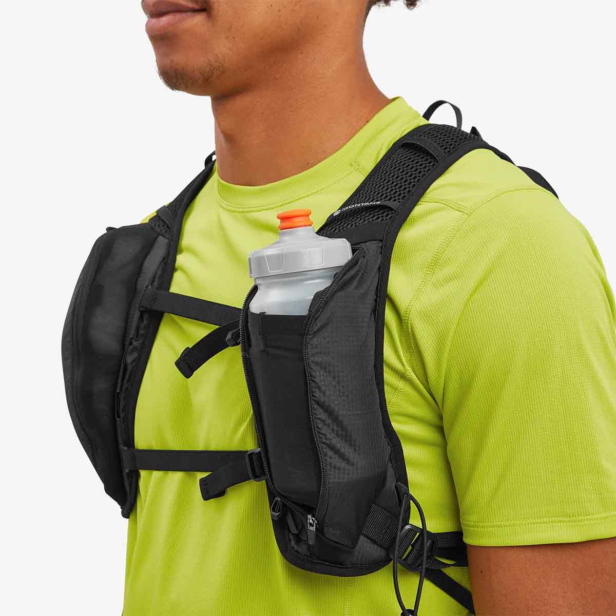 Close-up of a person wearing the Montane Trailblazer 8L Recycled Backpack, showing front storage pockets with a water bottle for easy hydration access.