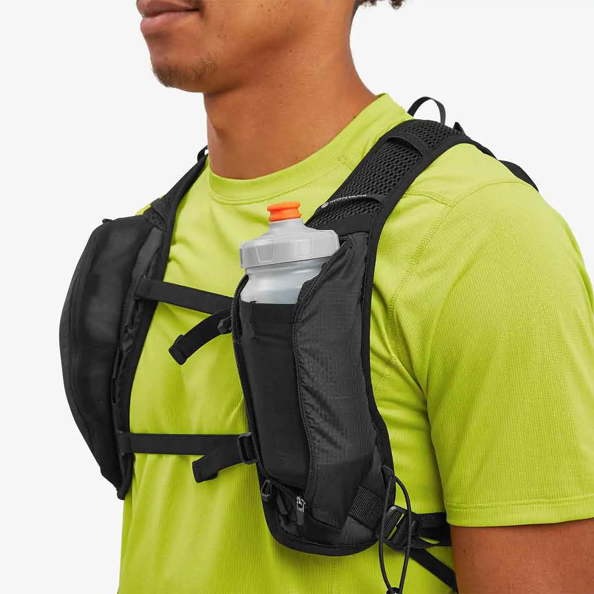 Close-up of a person wearing the Montane Trailblazer 8L Recycled Backpack, showing front storage pockets with a water bottle for easy hydration access. from John Bull Clothing
