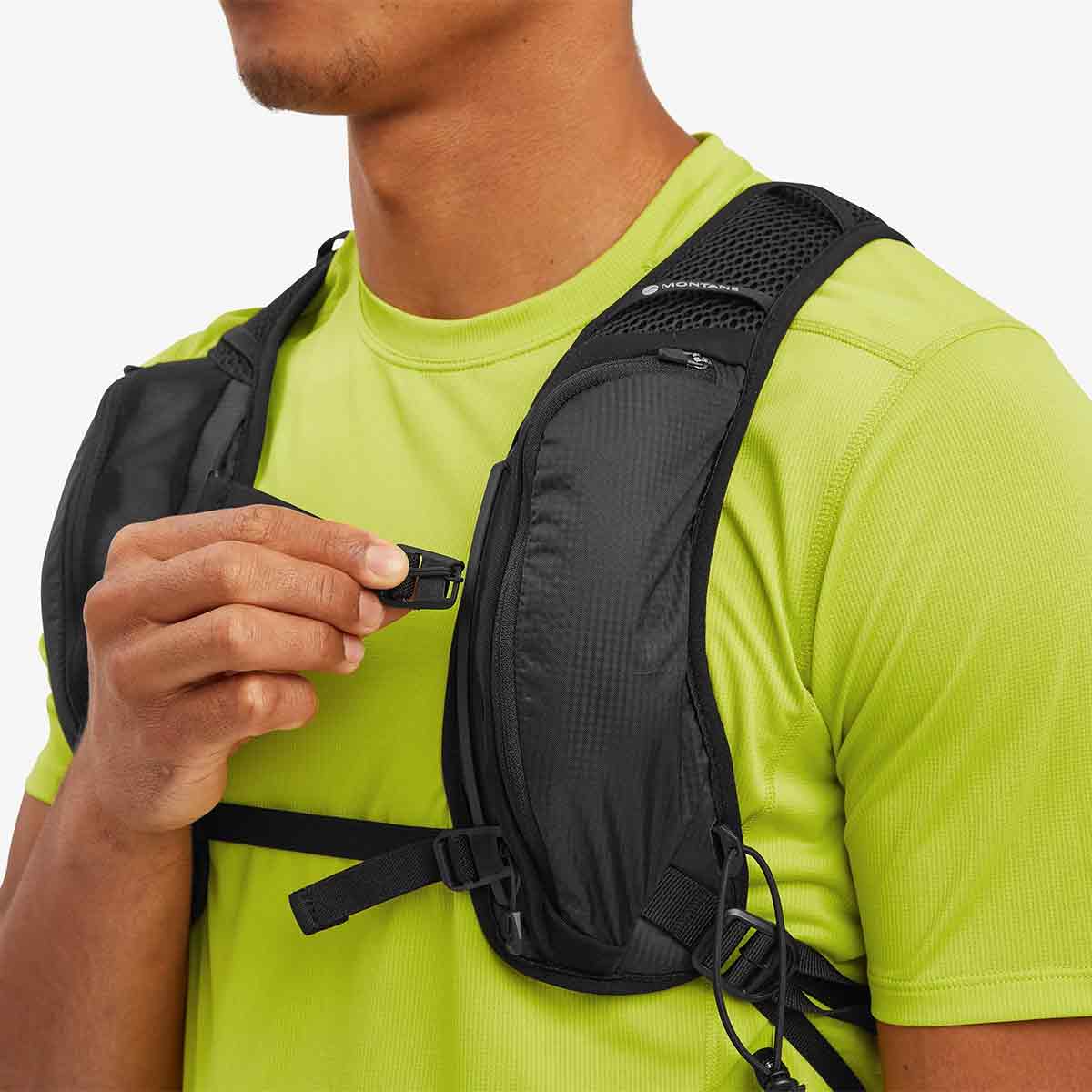 User adjusting the chest strap of the Montane Trailblazer 8L Recycled Backpack, demonstrating its secure fit and easy-to-use fastening system for stability.