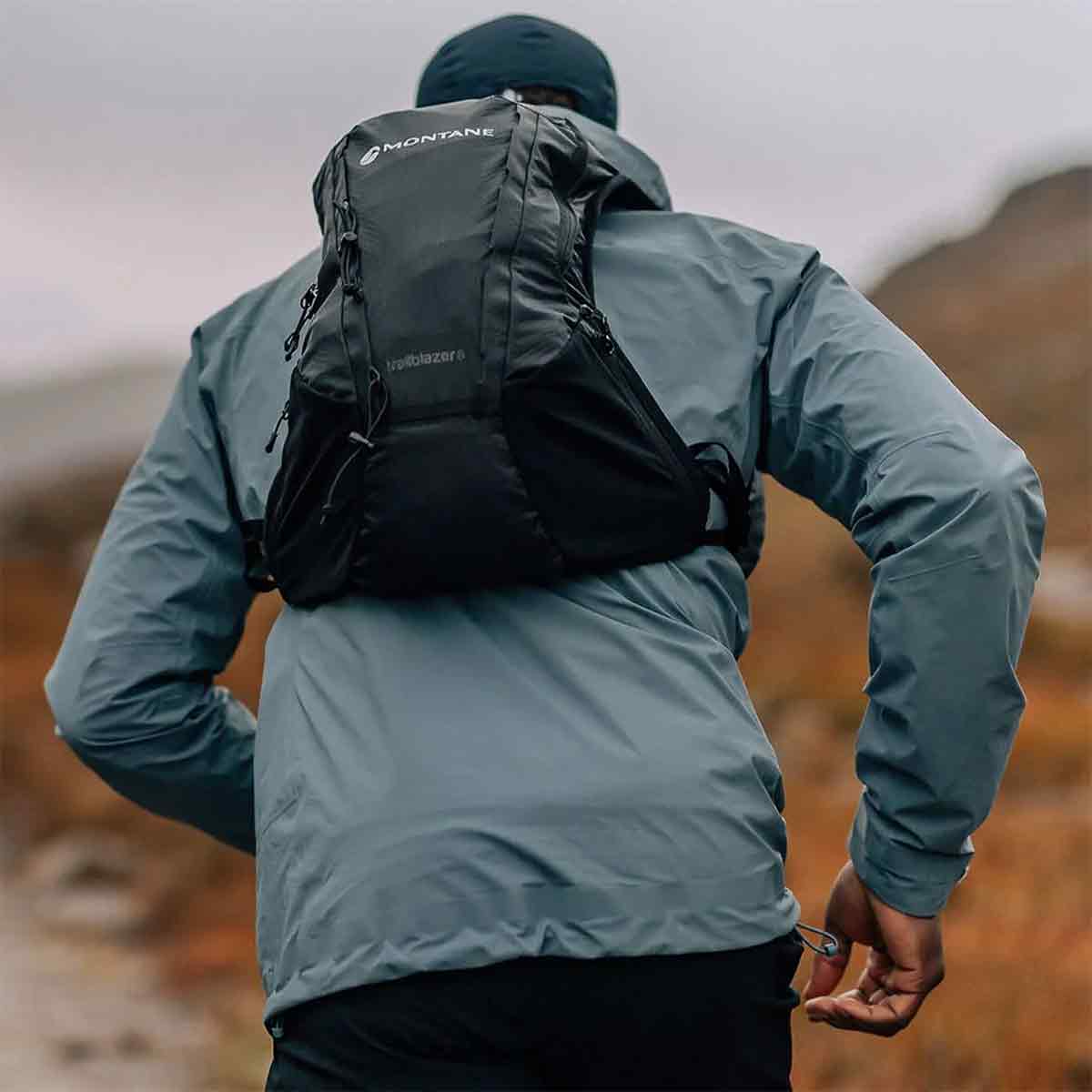 Runner wearing the Montane Trailblazer 8L Recycled Backpack in black, showcasing its snug fit and lightweight design for high-performance outdoor activities.