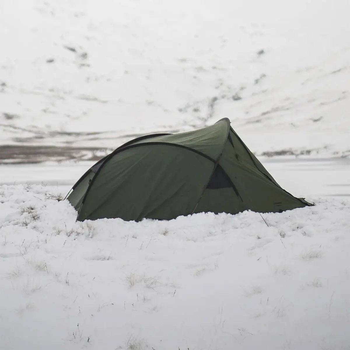 Snugpak Scorpion 3 IX Hiking Tent in Olive set up in snowy terrain, showcasing its all-weather durability for outdoor adventures.