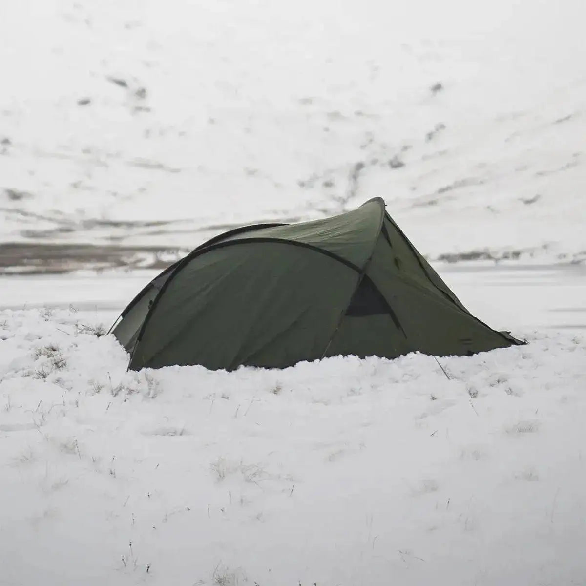 Snugpak Scorpion 3 IX Hiking Tent in Olive set up in snowy terrain, showcasing its all-weather durability for outdoor adventures. from John Bull Clothing