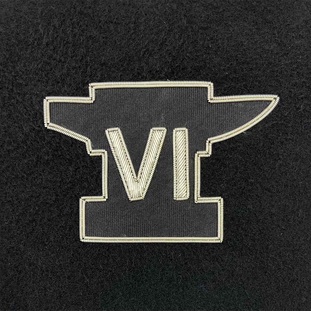 Embroidered military insignia featuring a black anvil with Roman numeral VI in silver thread. Ideal for Army presentation frames and memorabilia.