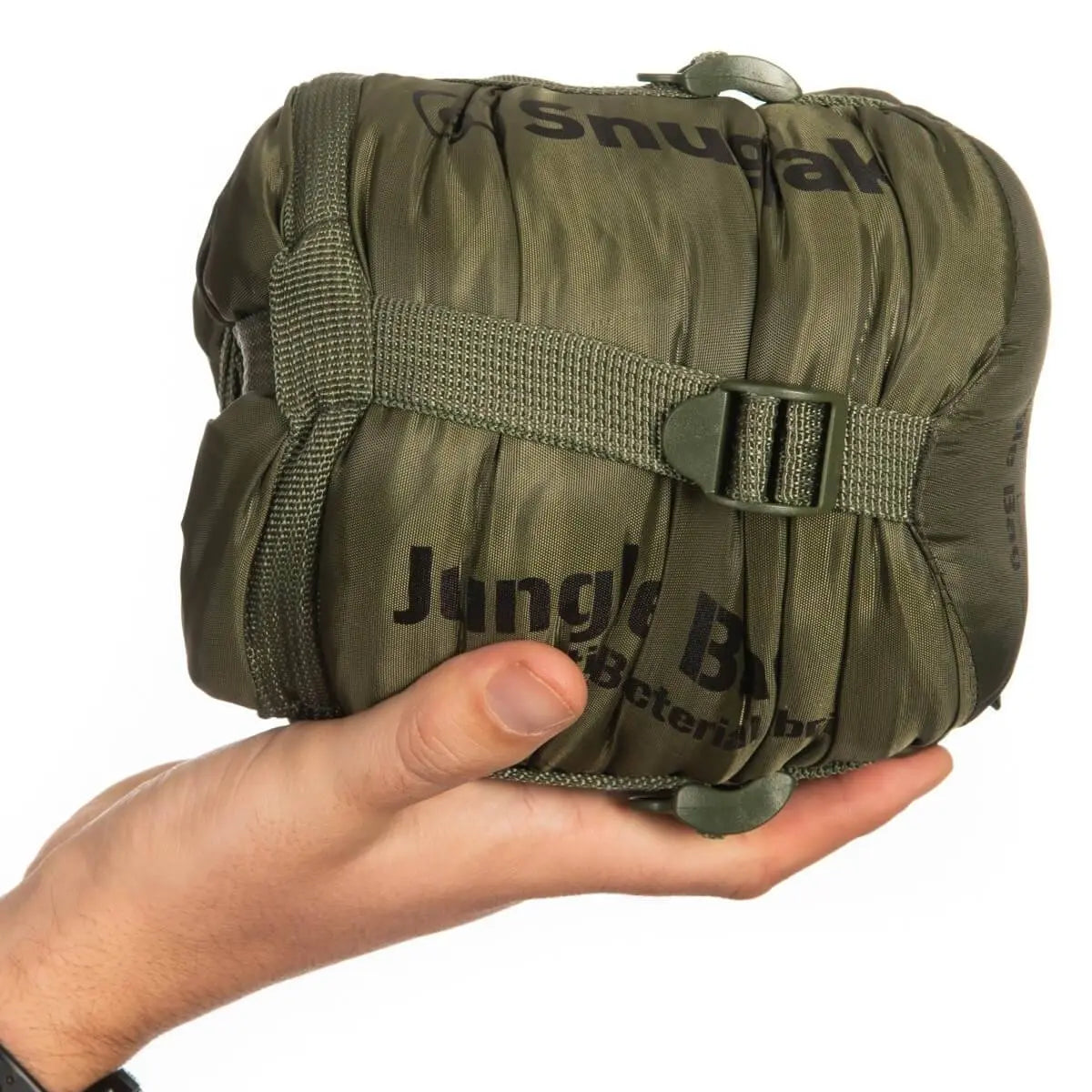 Olive green Snugpak Jungle Sleeping Bag with Mosquito Net packed into a compact bundle, shown in hand for size comparison.