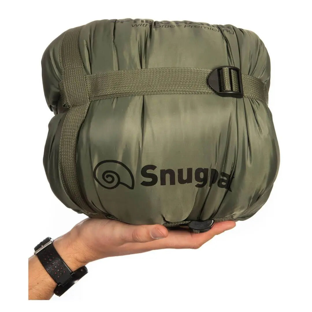 Compact packed Snugpak Softie 10 Harrier Sleeping Bag in olive green with logo, shown in hand for size reference, perfect for travel and hiking.