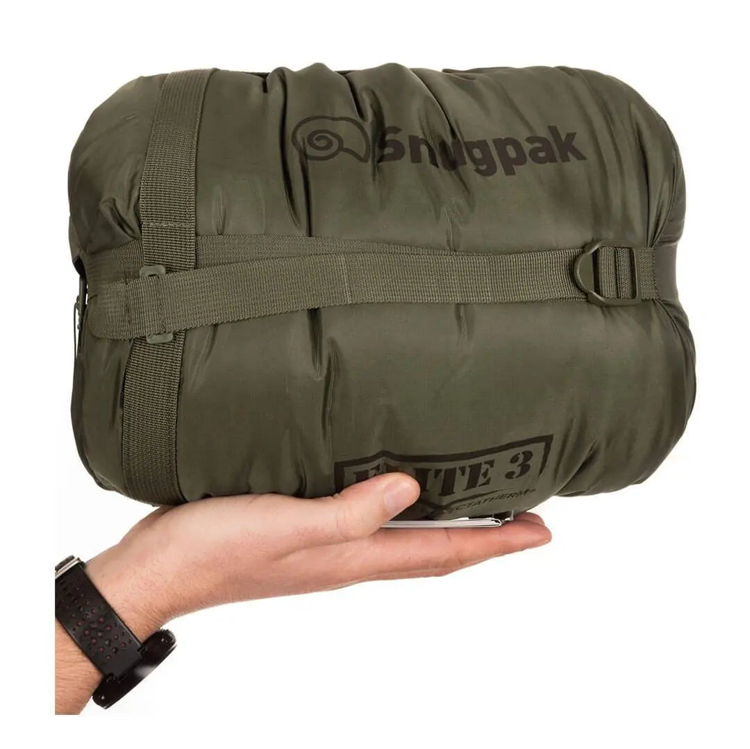 Compressed Snugpak Softie Elite 3 Sleeping Bag Olive Green in stuff sack with hand for scale, perfect for portable outdoor adventures.