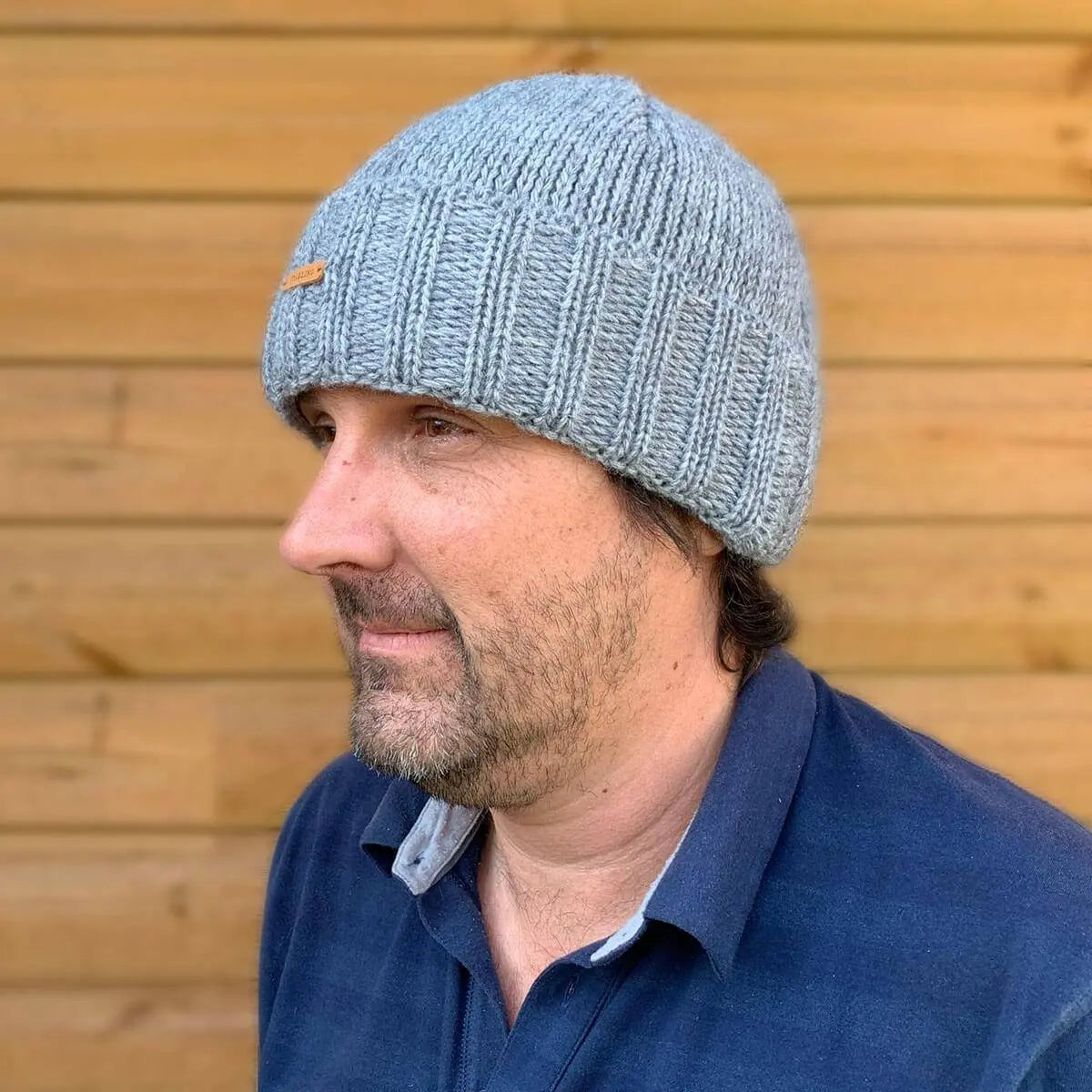 Man wearing the Starling Unisex Rollover Beanie Hat 12033 in grey, made from a warm double-lined wool mix, ideal for cold weather.