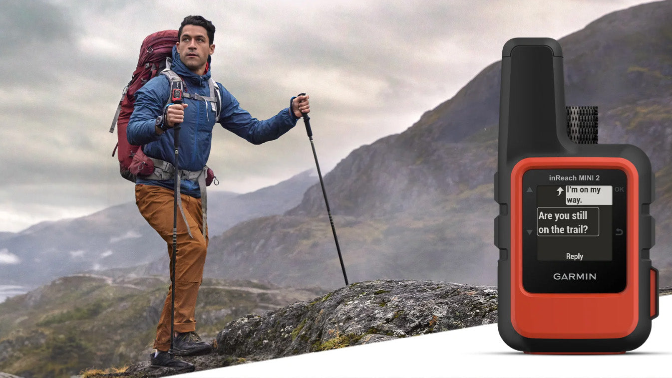 Adventurer hiking with Garmin inReach Mini 2 GPS in rugged mountains.