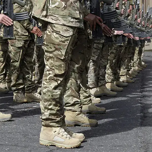 Soldiers in formation wearing tan army combat boots and camouflage uniforms.