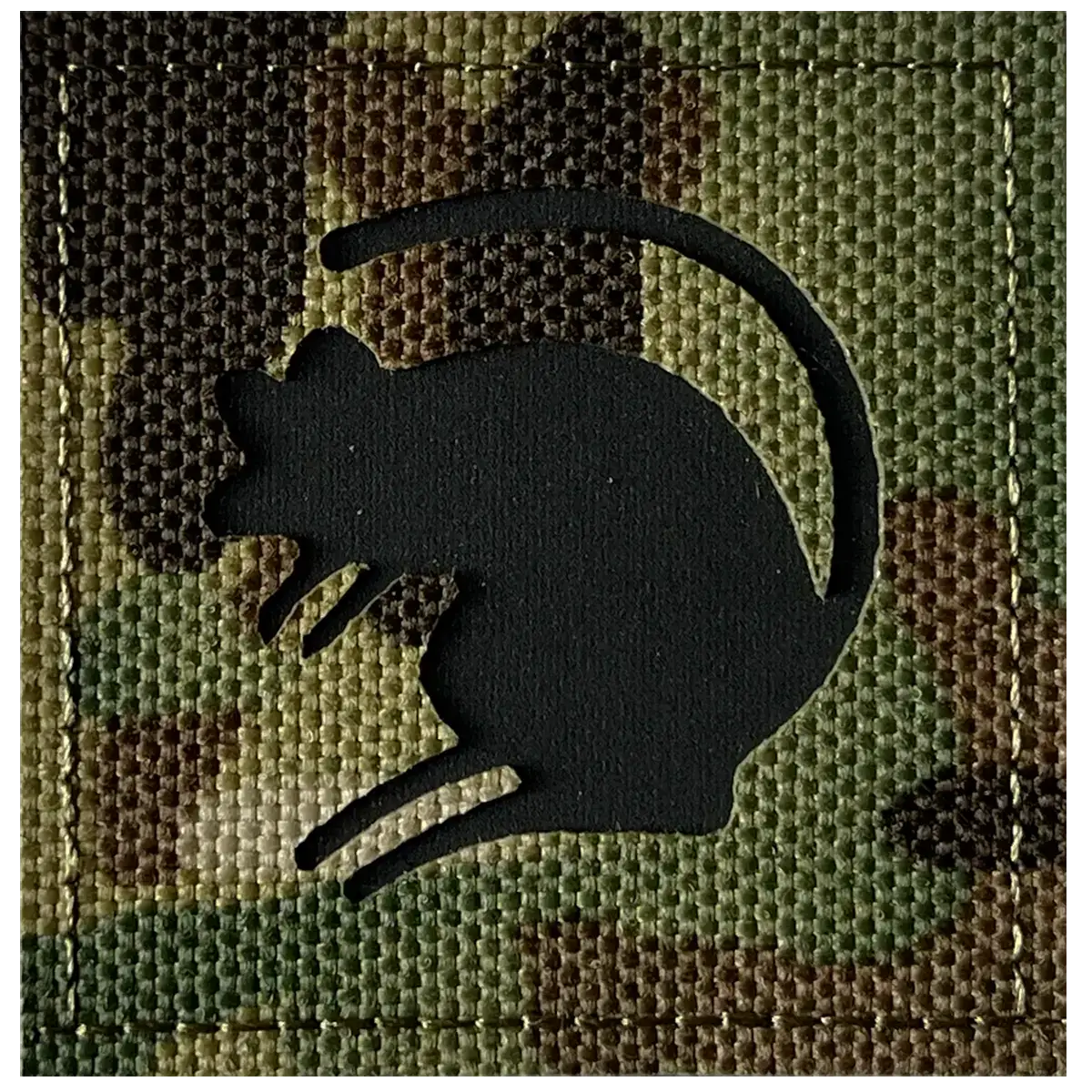 Close-up of black rubber rat silhouette patch on camouflage fabric, showing textured Velcro backing for military gear, SKU: JB1646